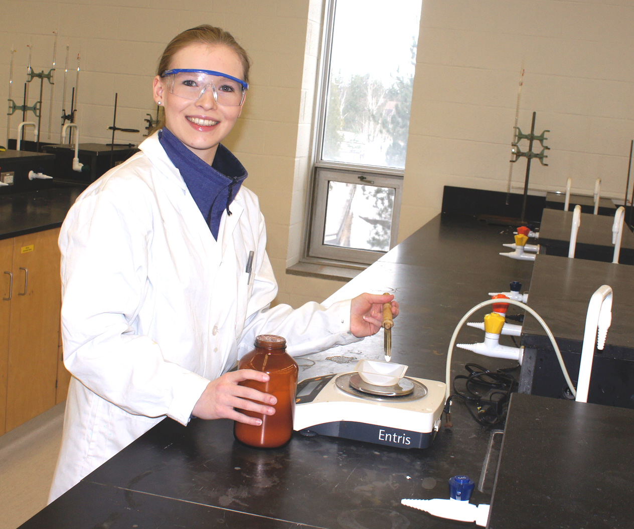 a young female student is measuring a chemical compound while working in a lab
